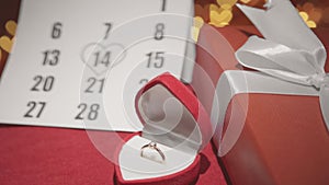 A gift for Valentines Day. Gift box on a red background with hearts. On the calendar, February 14