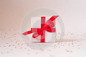 Gift white box with red satin ribbon and bow and stars on a white background