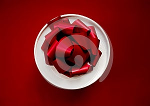 Gift in a white round box with a red bow on a red background. Top view.