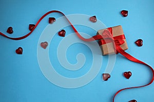 Gift wrapped in a box with a red bow on a blue background with hearts