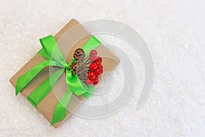 Gift wrapped in craft paper and decorated with green and red ribbons flat lay with snow on background