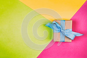 Gift wrapped and decorated with blue bow on colored background with copy space. Flat lay, top view