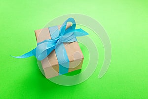 Gift wrapped and decorated with blue bow on green background with copy space. Flat lay, top view