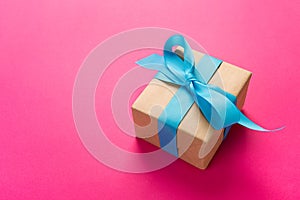 Gift wrapped and decorated with blue bow on pink background with copy space. Flat lay, top view