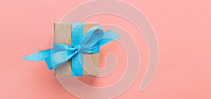 Gift wrapped and decorated with blue bow on pink background with copy space. Flat lay, top view