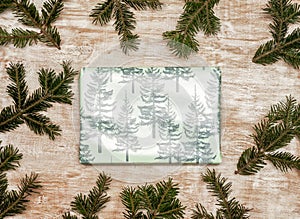 A gift wrapped in festive Christmas paper on a wooden background