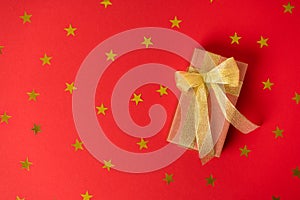 The gift is wrapped in gold paper with ribbons and a bow with stars