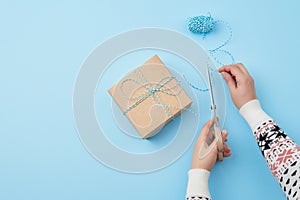 Gift wrapped and tied with a brown rope, female hand with scissors cuts a brown rope