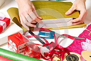 Gift wrapping for Christmas and New Year. Handmade. girl`s hands with gift ribbon, twine, tape and present wrapped