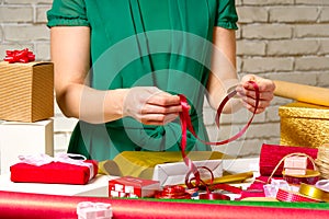 Gift wrapping for Christmas and New Year. Handmade. girl`s hands with gift ribbon, twine, tape and present wrapped