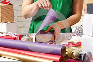 Gift wrapping for Christmas and New Year. Handmade. girl`s hands with gift ribbon, twine, tape and present wrapped