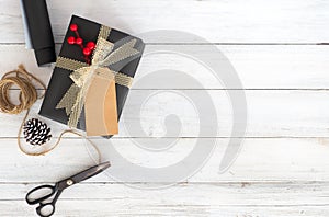 Hand crafted Christmas present gift box and tools on white wooden background.