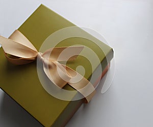 Gift wrapping in olive tones with an elegant beige ribbon on a clean white sheet of paper