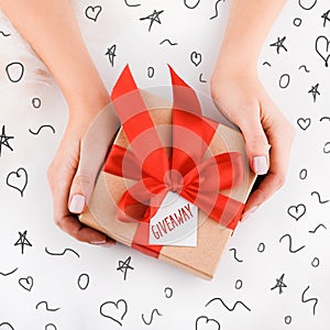 Gift wrapping. Packaging modern christmas present boxes in stylish gray paper with satin red ribbon. Top view of hands