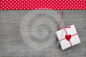 Giftbox wrapped in paper with a red heard on a wooden background photo