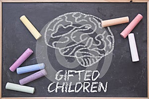 Gifted Children and education concept written on a blackboard in a classroom. Brain drawing and some colored chalk on a chalkboard