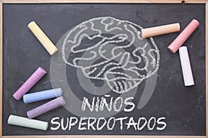 Gifted Children words written in Spanish and education concept on a blackboard in a classroom. Brain drawing and colored chalk photo