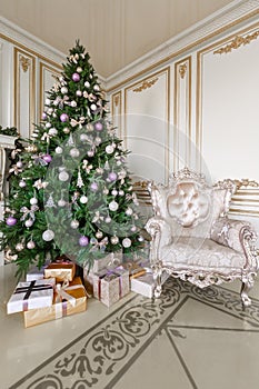 Gifts at the Christmas tree. Christmas morning. classic luxurious apartments with a white fireplace, sofa, large windows