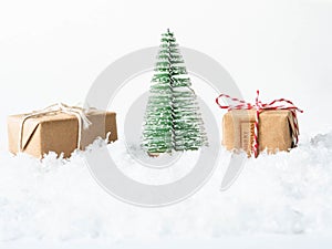 Gifts and Christmas tree in snow on white background. Merry Christmas or Happy New Year composition. Copy space