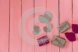 Gifts and hearts on pink wooden background