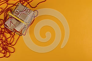 Gifts in a small shopping basket on a yellow background with Christmas decorations, concept, copy space