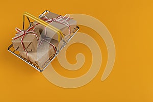 Gifts in a small shopping basket on a yellow background, concept, copy space