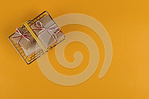 Gifts in a small shopping basket on a yellow background, concept, copy space