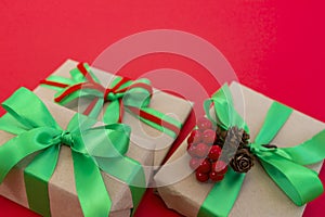 Gifts wrapped in craft paper and decorated with green and red ribbons flat lay on red background