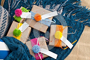 Gifts wrapped in kraft paper lie on a knitted rug.