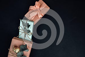 Gifts wrapping in soft pink and blue paper with dry eucalyptus branch on a black concrete background
