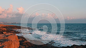 Gigantic ocean waves crashing on rocky beach. Big sea waves splashing and creating foam. Stormy mediterranean sea at sunset. Massi