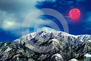 Gigantic super red moon winter landscape highlighting the snow caped mountains of winter. photo