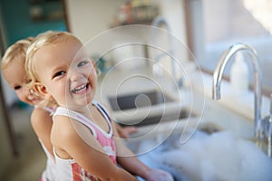 Giggles and grins. Portrait of two young girls having fun while doing housework.