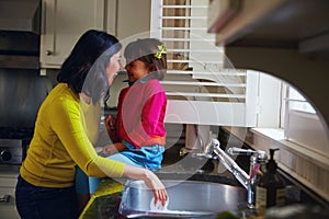 Giggles in the kitchen. a young mother and her daughter bonding by the kitchen sink.