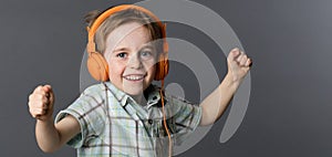Giggling young boy dancing with winning arms listening to music