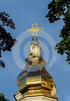 Gilded dome with a cross of an Orthodox church against a blue sky with white clouds