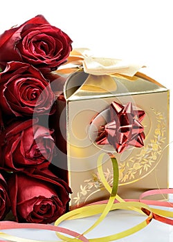Gilded gift box for holiday and red-maroon flowers roses on a white background