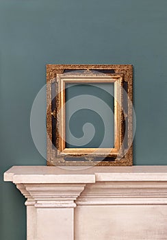 Gilded or golden vintage frame on a mantelpiece