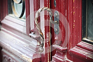 Gilded iron croocked door handle on red painted wooden door