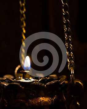 Gilded lamp with a burning wick photo