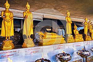 The gilden sculptures of Buddha in small Altar with burning oil lamps, San Lak Mueang shrine in Bangkok, Thailand