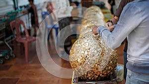 Gilding gold sheet on steel ball and Buddha statue. Religious ceremony of Thailand