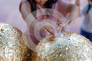 Gilding gold sheet on steel ball and Buddha statue. Religious ceremony of Thailand