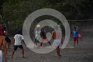 GILI ASAHAN, INDONESIA - AUGUST, 22 2016 - boys are playing soccer at sunset on a palm tree field near the beach