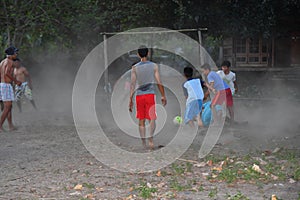 GILI ASAHAN, INDONESIA - AUGUST, 22 2016 - boys are playing soccer at sunset on a palm tree field near the beach