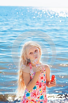 Gilrl with soap bubbles on seashore