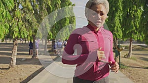 gimbal tracking attractive middle aged lady running happy at city park . beautiful and sporty 40s woman exercising jogging