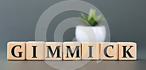 GIMMICK - word on wooden cubes on a gray background with a cactus