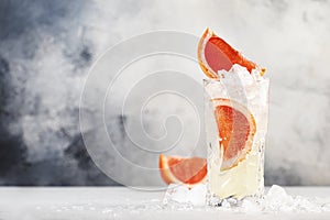 Gin bitter lemon trendy alcoholic cocktail drink with dry gin, tonic, grapefruit and ice cubes. Gray background with copy space