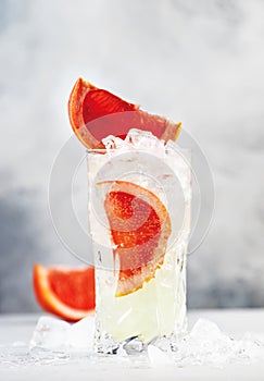 Gin bitter lemon trendy alcoholic cocktail drink with dry gin, tonic, grapefruit and ice cubes. Gray background with copy space